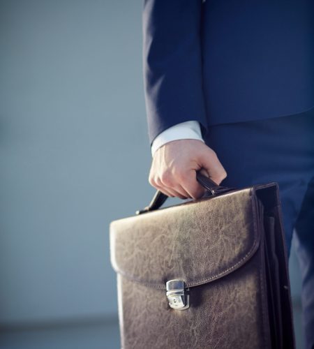 Vertical cropped image of a businessperson carrying a leather briefcase isolated on grey